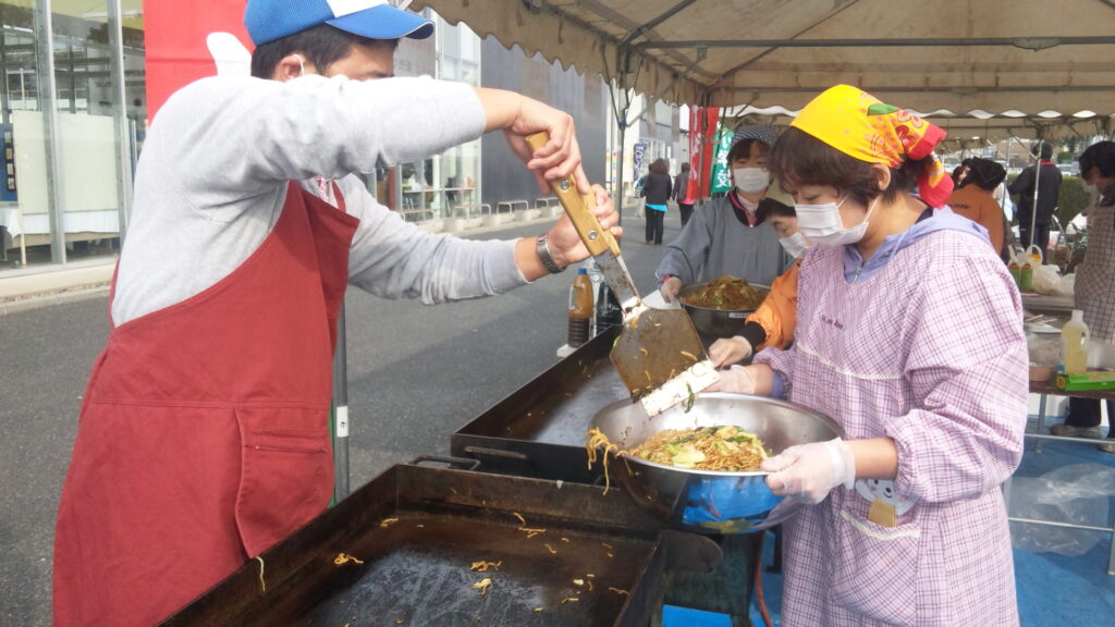 韮川ふれあいまつり2013 焼きそばを焼いてボールに移す山﨑議員